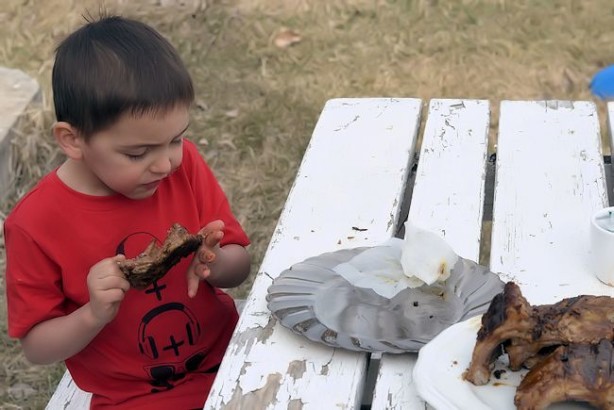 boys eating ribs outside