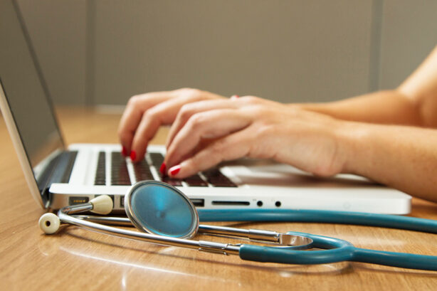 stethescope-beside-woman-typing-on-laptop