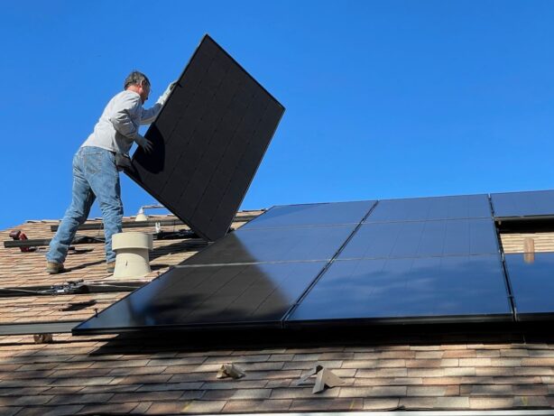man installing solar panels on home