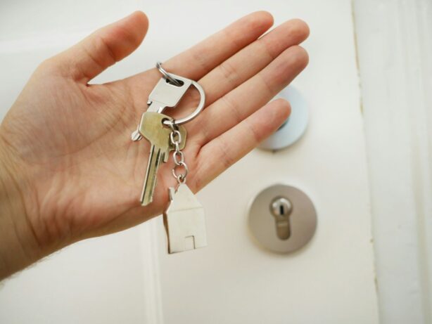 hand holding key in front of door